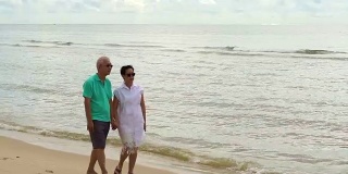 一对亚洲老年夫妇在海滩上愉快地散步。计划好退休生活，没有财务问题