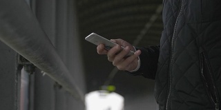 一个男人在人行桥上使用智能手机的特写