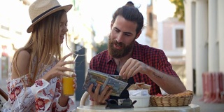 一对快乐的夫妇在度假时在咖啡馆外阅读旅游指南