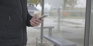 一个男人在公交车站使用智能手机的特写