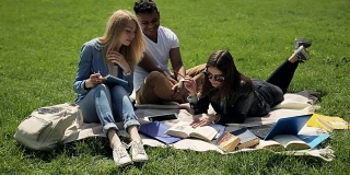 三个学生在校园草坪上学习。
