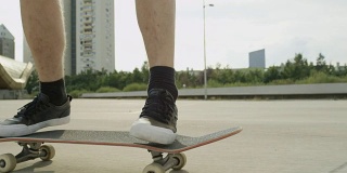 慢镜头特写:年轻的滑板运动员跳跃和在城市街道上做特技