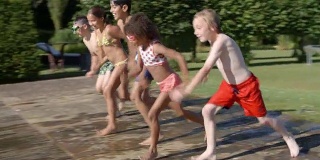 一群孩子跳进室外游泳池