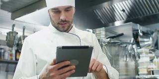 一家餐厅或酒店的商业厨房里的专业厨师正在使用平板电脑。