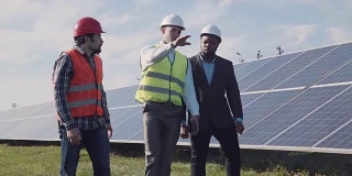 工人们在一排排太阳能板之间行走