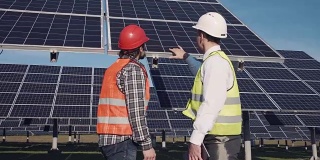 技术人员在外面讨论太阳能电池板阵列