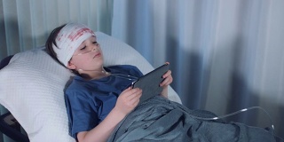 在平板电脑上玩4k呼吸管游戏的受伤儿童医院照片