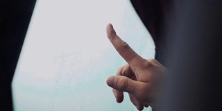 一名男子用一根手指触摸车窗。外面下雨的天气。滴