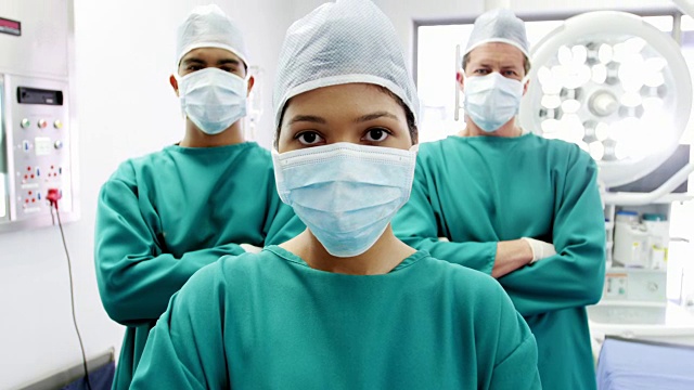 外科医生和护士双手交叉站在手术室的肖像