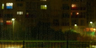 外面下雨时，水珠落在窗户上。散焦多层建筑与窗户照明和活动的背景。延时4k视频。