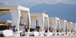在傍晚的阳光下，绿松石大海前的木制日光浴床。在著名的意大利海滩Forte dei Marmi日光浴床