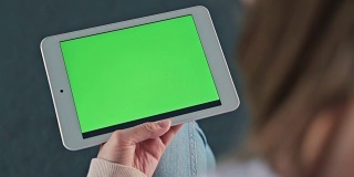 Woman looking at tablet with green screen