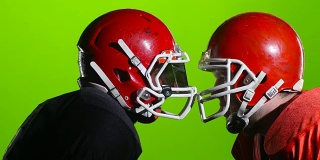 两名美式橄榄球运动员在赛场上戴着头盔。绿色的屏幕。近距离