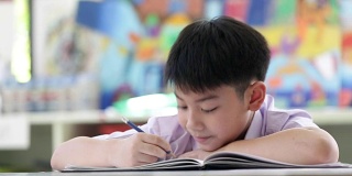 亚裔孩子穿着学生校服做读书写字的学校作业。