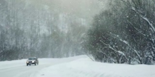 下雪时在雪地上缓慢行驶的汽车。1920 x1080