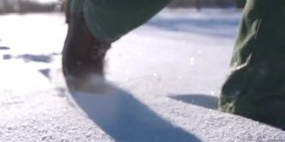 一个人的脚在雪山上行走的特写。慢动作拍摄