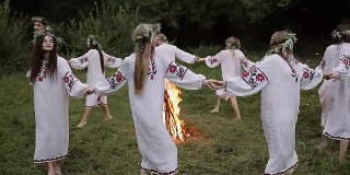 仲夏。在仲夏，穿着斯拉夫服装的年轻人围着一堆火转。