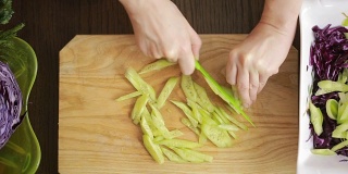 女人的手用刀切红卷心菜沙拉。切黄瓜