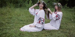 仲夏。两个穿着斯拉夫服装的女孩在火炉旁编着辫子。