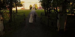 无人机拍摄到新郎和新娘走向公园里的豪宅。