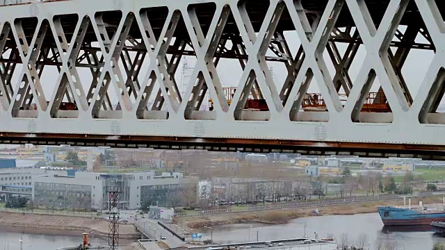 近景航拍位于桁架桥的大型现代汽车起重机，以城市景观为背景
