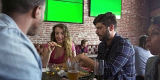 朋友在体育酒吧吃饭与屏幕上拍摄的R3D
