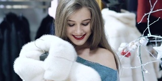 一个漂亮的女孩在商店里慢慢地挑选了一件皮大衣