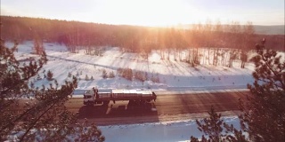 Slowmotion。许多卡车在夕阳下行驶在雪地上。雪花飘落下来