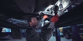 在汽车底部工作的非洲机械师