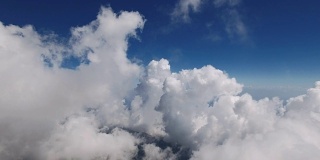 在一个阳光明媚的日子里，在高海拔的山脉中穿过柔软蓬松的云，用4K超高清拍摄