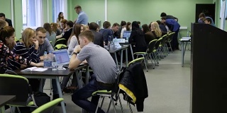 大学的现代教育过程。听众中有很多学生坐在桌子旁，用笔记本电脑学习信息。大型宽敞的类