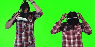 两个戴着VR眼镜的男人在绿色屏幕上