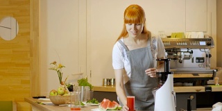 厨房桌上放着一杯新鲜的西瓜汁。一个年轻女子在背景中切着一个成熟的西瓜。富含维生素的健康生态食品。受欢迎的有机农业产品。