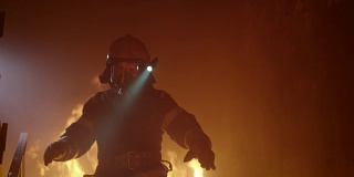 勇敢的消防员在头盔上打开手电筒跑下燃烧的楼梯。火是激烈的。在缓慢的运动。