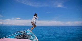 年轻性感勇敢的女孩在黑色比基尼和白色衬衫跳进开放的海洋。美丽的女性旅行者潜水在绿松石海从游艇甲板在海上巡航