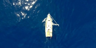 史诗般的蓝色海景与白色帆船进入镜头从底部。白帆船从上空掠过