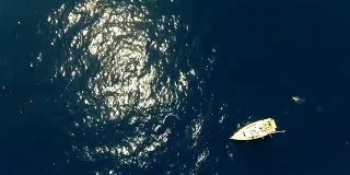 帆船鸟瞰图在蓝色的海洋与阳光闪烁和一个游泳者绕着船