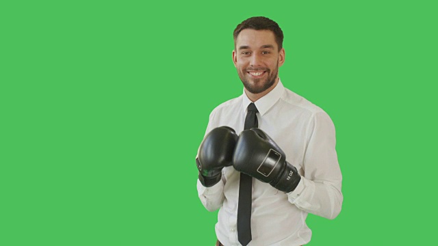 一个英俊的男人在一件衬衫和领带与拳击手套上，然后微笑的镜头。背景为绿幕。