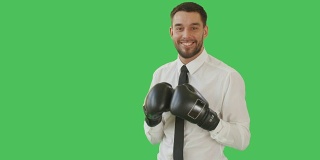 一个英俊的男人在一件衬衫和领带与拳击手套上，然后微笑的镜头。背景为绿幕。