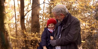孙女在秋天和爷爷一起散步坐在篱笆上