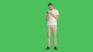 一个漫不经心的男人在他的智能手机上用滑动指向手势的长镜头。背景为绿幕。视频素材模板下载