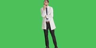 长镜头英俊的科学家戴着防护眼镜做触摸下巴思考手势。背景为绿幕。