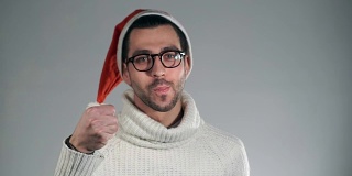 戴着圣诞帽的神奇商人竖起大拇指，显示出焦点，咬掉他的手指