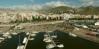 航拍:一个有帆船和游艇的码头的摇摄。在港口附近可以看到城市建筑