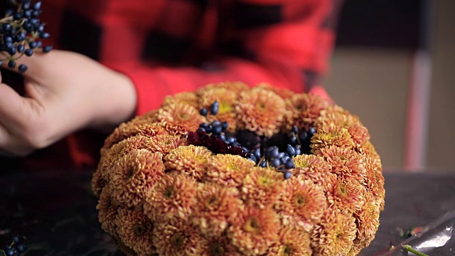花匠在木桌上用花朵、浆果组成