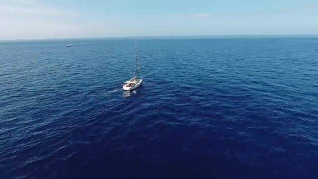 航拍:镜头在蓝色的大海中追逐一艘帆船。镜头围绕着帆船旋转