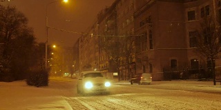 汽车行驶在白雪覆盖的街道上，中欧，夜晚