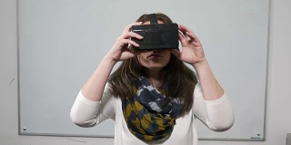 一名女子在教室里测试虚拟现实眼镜，教室后面有白板