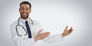 中景一个医生做展示手势和微笑。拍摄在白色背景。
