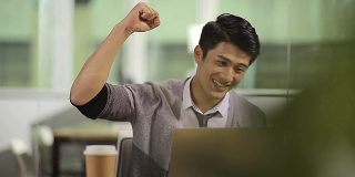 年轻的亚洲商人庆祝在办公室的成功